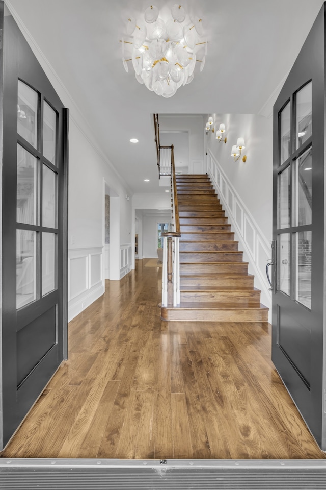 foyer featuring ornamental molding, wood-type flooring, and an inviting chandelier