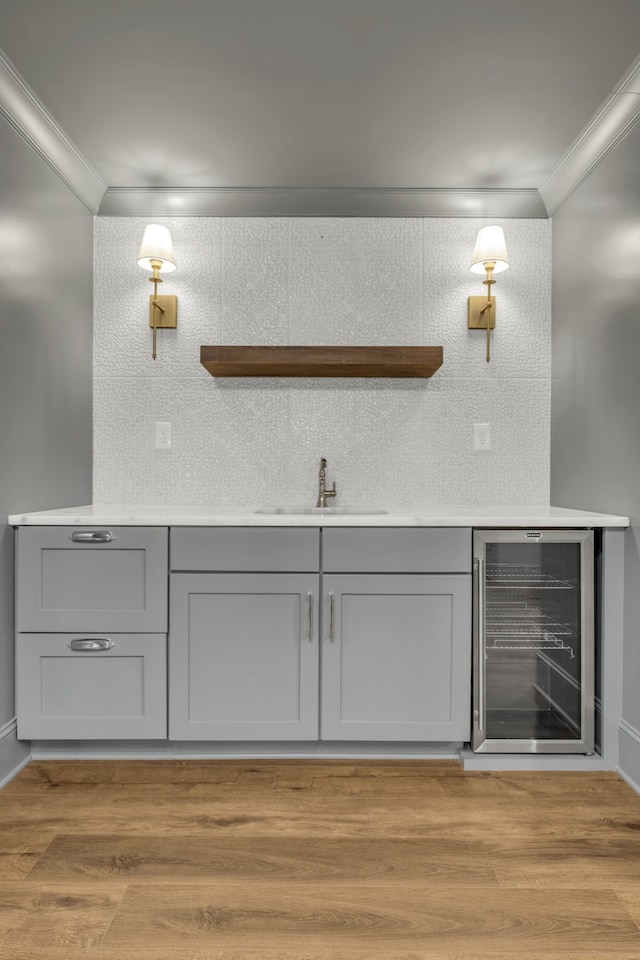 bathroom featuring hardwood / wood-style floors, beverage cooler, sink, and crown molding