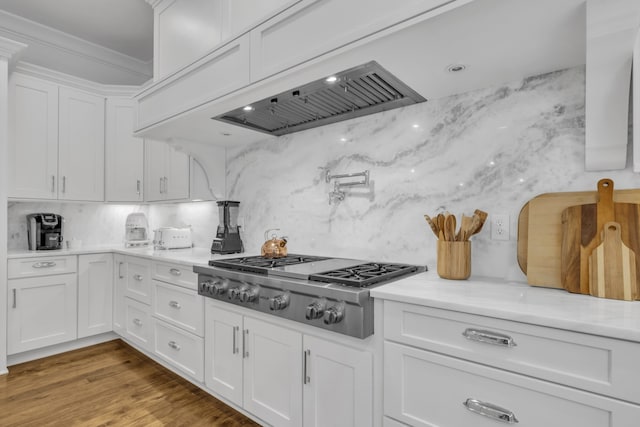 kitchen featuring light hardwood / wood-style floors, stainless steel gas stovetop, crown molding, white cabinets, and decorative backsplash