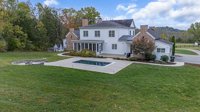 back of house featuring a patio, a mountain view, a yard, and a fire pit