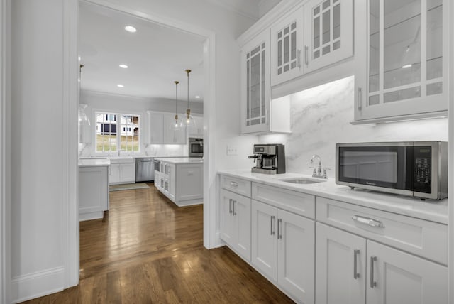 kitchen with ornamental molding, white cabinetry, appliances with stainless steel finishes, dark hardwood / wood-style flooring, and sink