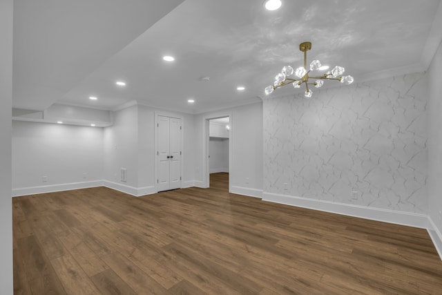 empty room featuring ornamental molding, dark hardwood / wood-style floors, and a chandelier