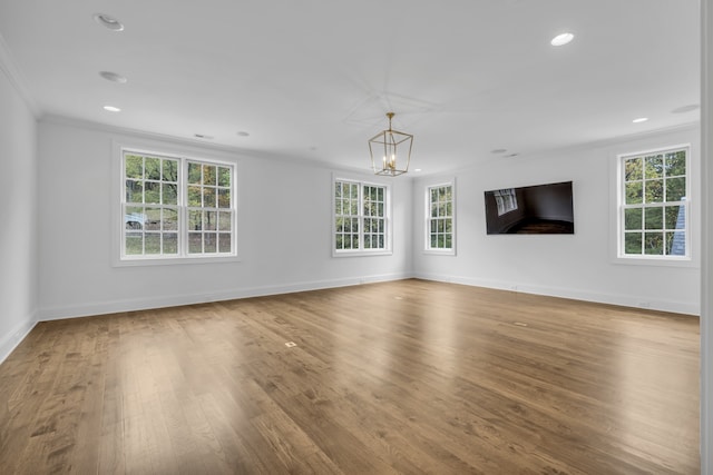 unfurnished living room featuring an inviting chandelier, wood-type flooring, and crown molding