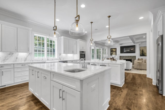 kitchen with white cabinetry, sink, a kitchen island with sink, and decorative light fixtures