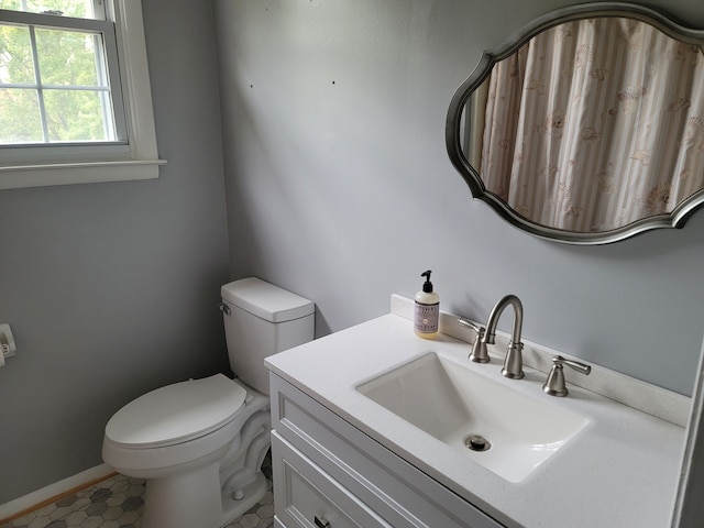 bathroom with toilet, vanity, and tile patterned floors