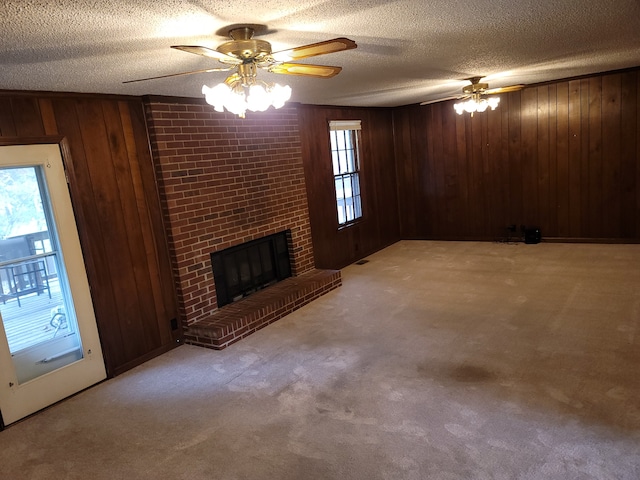 unfurnished living room with carpet flooring, a textured ceiling, wooden walls, and ceiling fan