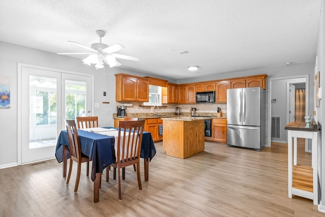 kitchen with stainless steel refrigerator, light hardwood / wood-style flooring, sink, ceiling fan, and a center island