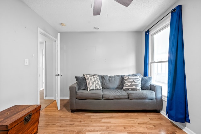 living room featuring ceiling fan, a textured ceiling, and light hardwood / wood-style floors