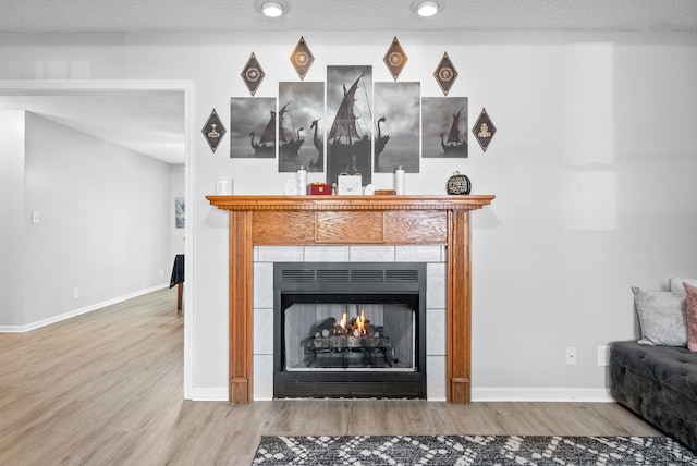 interior space featuring a textured ceiling, hardwood / wood-style flooring, and a tile fireplace