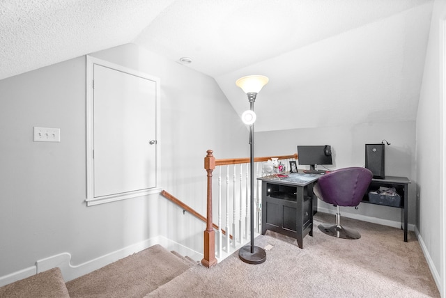 carpeted office with vaulted ceiling and a textured ceiling