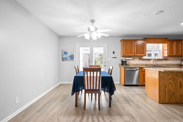 dining area featuring a textured ceiling, light wood-type flooring, ceiling fan, and sink