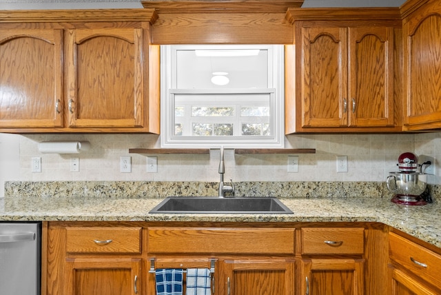 kitchen featuring tasteful backsplash, light stone countertops, sink, and stainless steel dishwasher