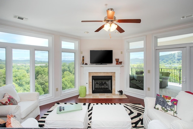 living room with ornamental molding, a healthy amount of sunlight, ceiling fan, and a tile fireplace