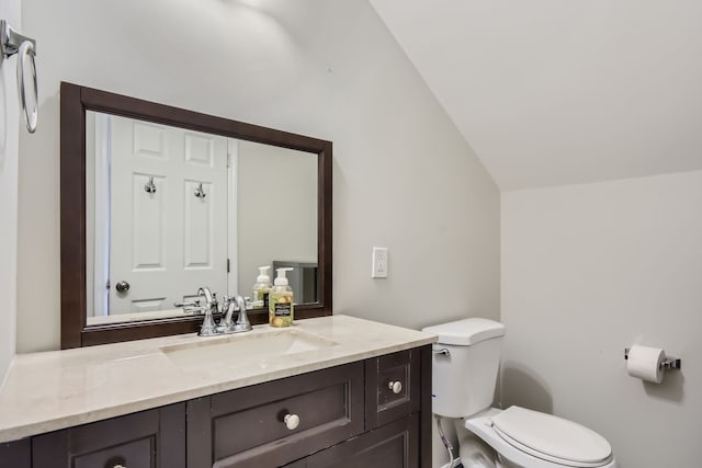 bathroom with vanity, toilet, and lofted ceiling