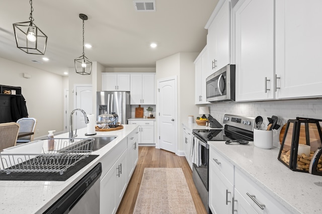 kitchen with white cabinetry, light wood-type flooring, stainless steel appliances, and light stone countertops