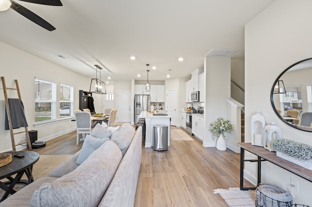 living room with ceiling fan and light hardwood / wood-style flooring