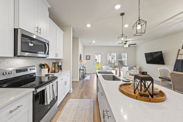 kitchen featuring stainless steel appliances, light stone counters, sink, white cabinetry, and light hardwood / wood-style flooring