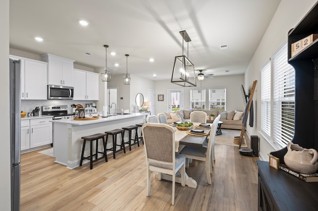 dining area featuring ceiling fan, sink, and light wood-type flooring