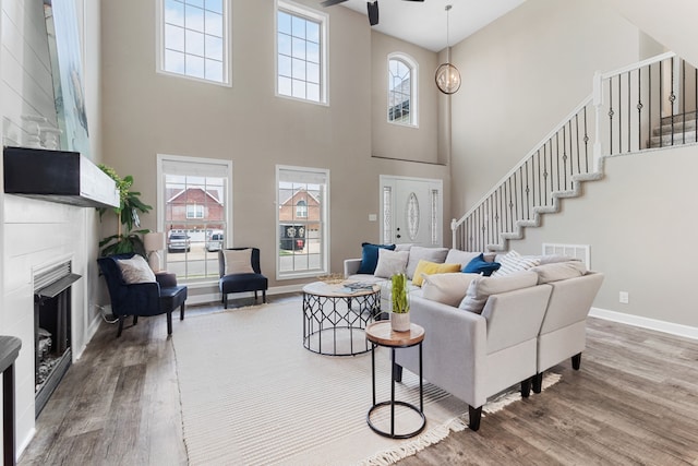 living room featuring a high ceiling, wood-type flooring, and a healthy amount of sunlight