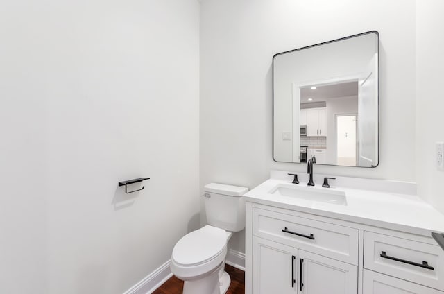 bathroom with hardwood / wood-style flooring, vanity, and toilet