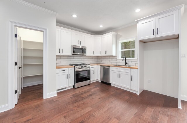 kitchen with white cabinetry, appliances with stainless steel finishes, and wood counters