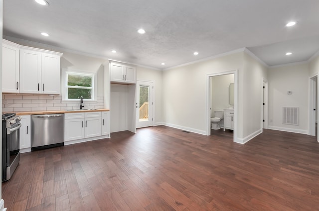 kitchen featuring butcher block countertops, white cabinetry, sink, decorative backsplash, and stainless steel appliances