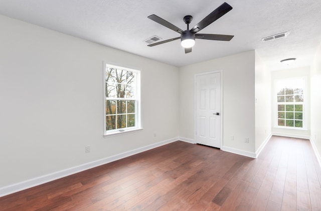 unfurnished room featuring ceiling fan, dark hardwood / wood-style floors, and a wealth of natural light