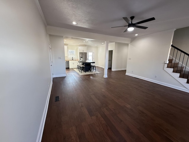 unfurnished living room with dark hardwood / wood-style flooring, ceiling fan, crown molding, and a textured ceiling