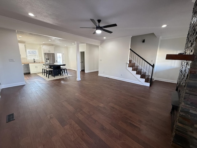 unfurnished living room with dark wood-type flooring, ceiling fan, ornamental molding, and sink