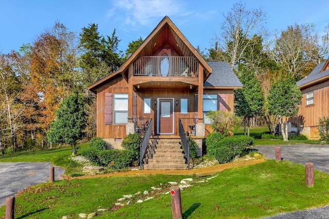 view of front of home with a balcony and a front lawn