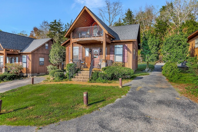 view of front of property featuring a balcony and a front lawn