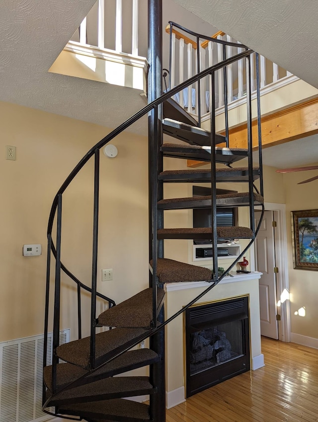 stairs with hardwood / wood-style floors and a textured ceiling