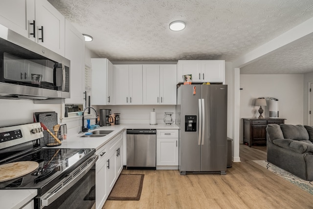 kitchen featuring white cabinets, light wood-type flooring, stainless steel appliances, and sink