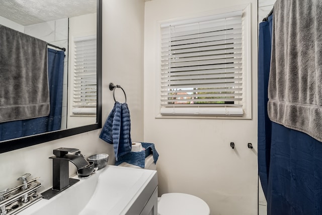 bathroom featuring a shower with curtain, a textured ceiling, toilet, and vanity