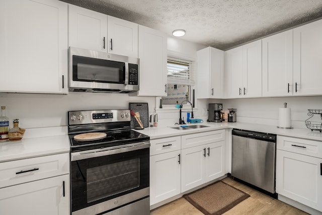 kitchen with white cabinetry, appliances with stainless steel finishes, sink, and a textured ceiling