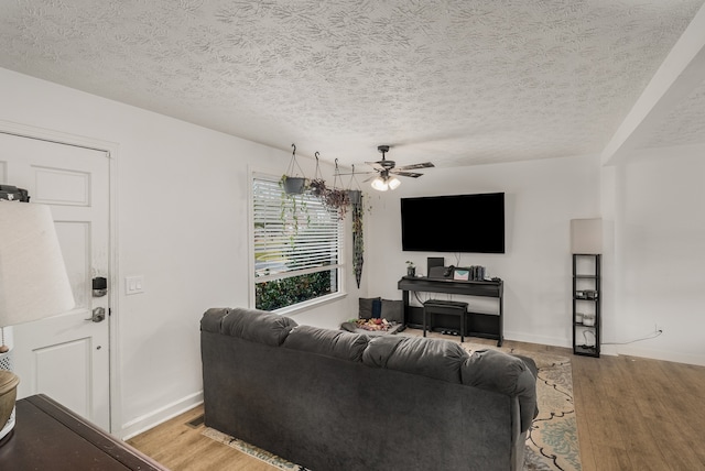 living room with a textured ceiling, light wood-type flooring, and ceiling fan