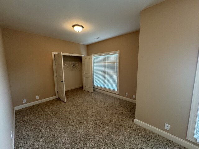 unfurnished bedroom featuring light carpet and a closet