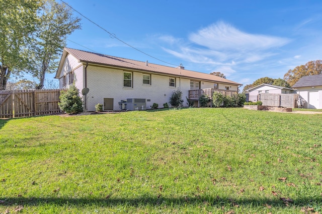 rear view of house with central air condition unit, a lawn, and a wooden deck