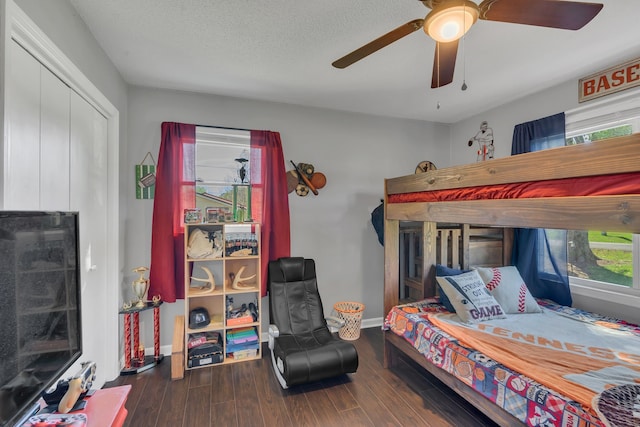 bedroom featuring a textured ceiling, dark hardwood / wood-style flooring, a closet, and ceiling fan