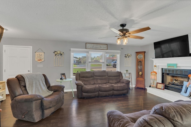 living room featuring a textured ceiling, a brick fireplace, ceiling fan, and dark wood-type flooring