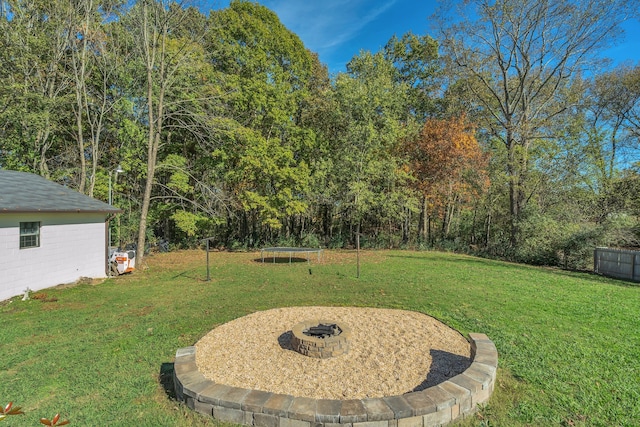 view of yard with a trampoline and a fire pit