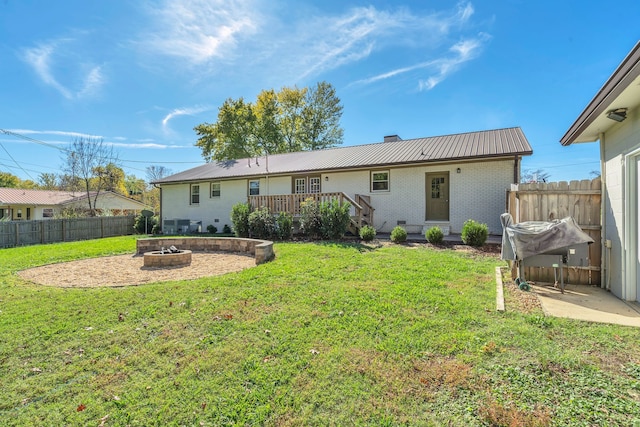 rear view of house featuring a wooden deck, a yard, and an outdoor fire pit