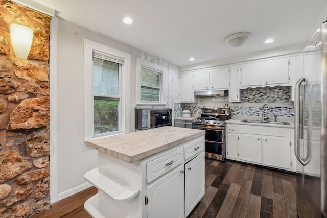 kitchen with white cabinets, dark wood-type flooring, appliances with stainless steel finishes, and tasteful backsplash