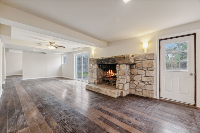 unfurnished living room with dark hardwood / wood-style flooring, a wealth of natural light, ceiling fan, and a fireplace