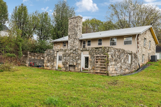 rear view of house with cooling unit and a lawn