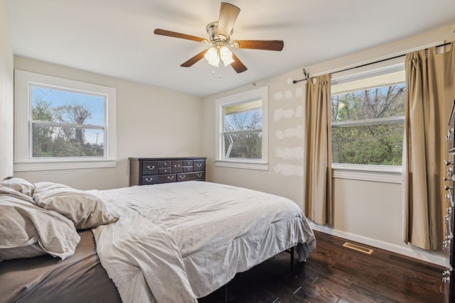 bedroom featuring ceiling fan, multiple windows, and dark hardwood / wood-style flooring