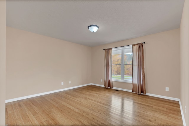 empty room featuring light wood-type flooring and a textured ceiling