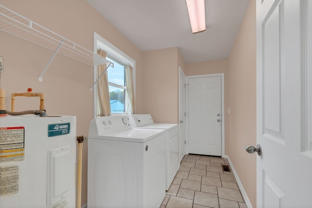 washroom with water heater, washing machine and dryer, and light tile patterned flooring