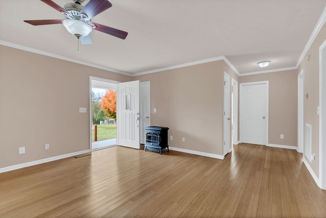 unfurnished living room featuring light wood-type flooring, a wood stove, ceiling fan, and crown molding