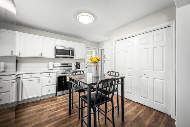 kitchen featuring dark hardwood / wood-style flooring, white cabinets, and appliances with stainless steel finishes